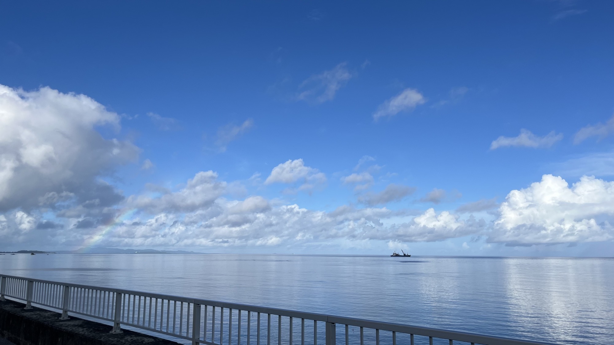 穏やかな海と、空にかかる小さな虹